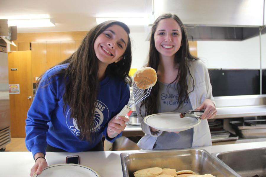 Sophie Frank and Danielle Fogelson, seniors, smile for camera while they serve food. 