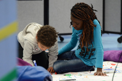 Young students color during the poetry slam.