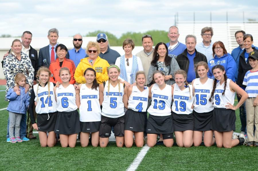 Girls lacrosse team poses with their families on senior day.
