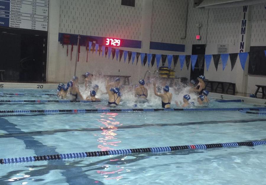The girls swim team celebrates in the pool after hearing the result of the dual meet.