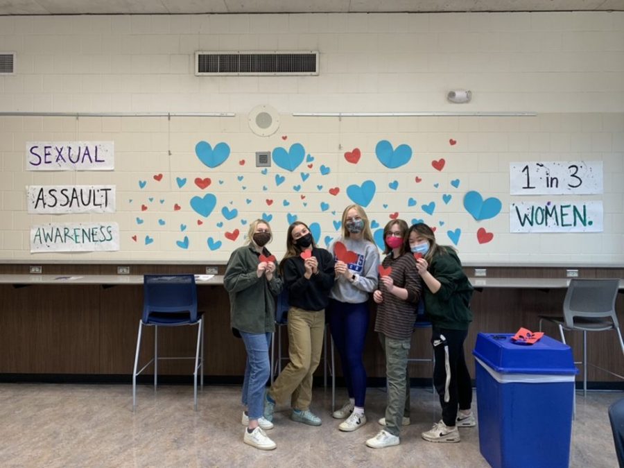 Five HHS seniors pose in front of their mural created in honor of Sexual Assault Awareness Month